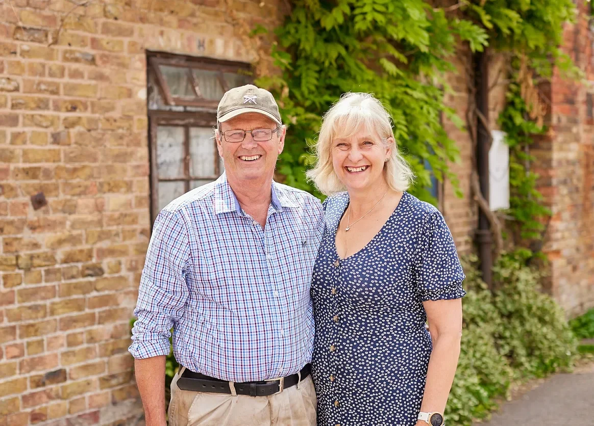 Wendy and Richard smiling outside the Moor Farm farmhouse