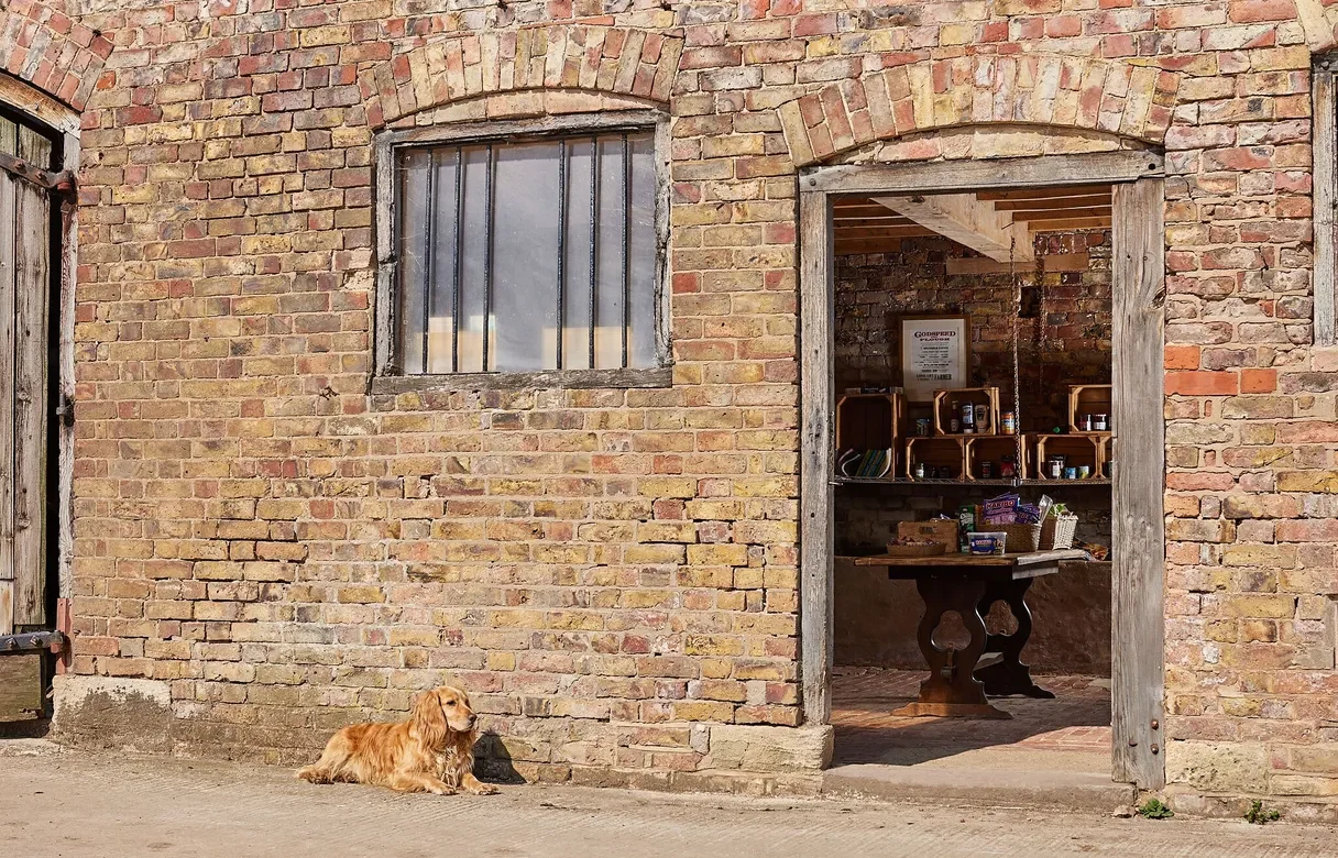 Brick farmhouse building with an open doorway leading into the honesty shop