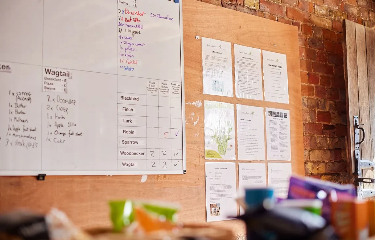 Large noticeboard with information pinned up and a whiteboard for recording shop products and food bookings