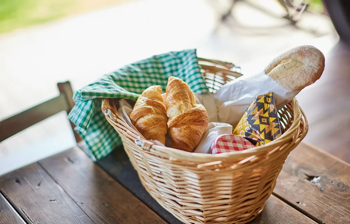 Basket of fresh bread and croissants on a bench in a safari tent
