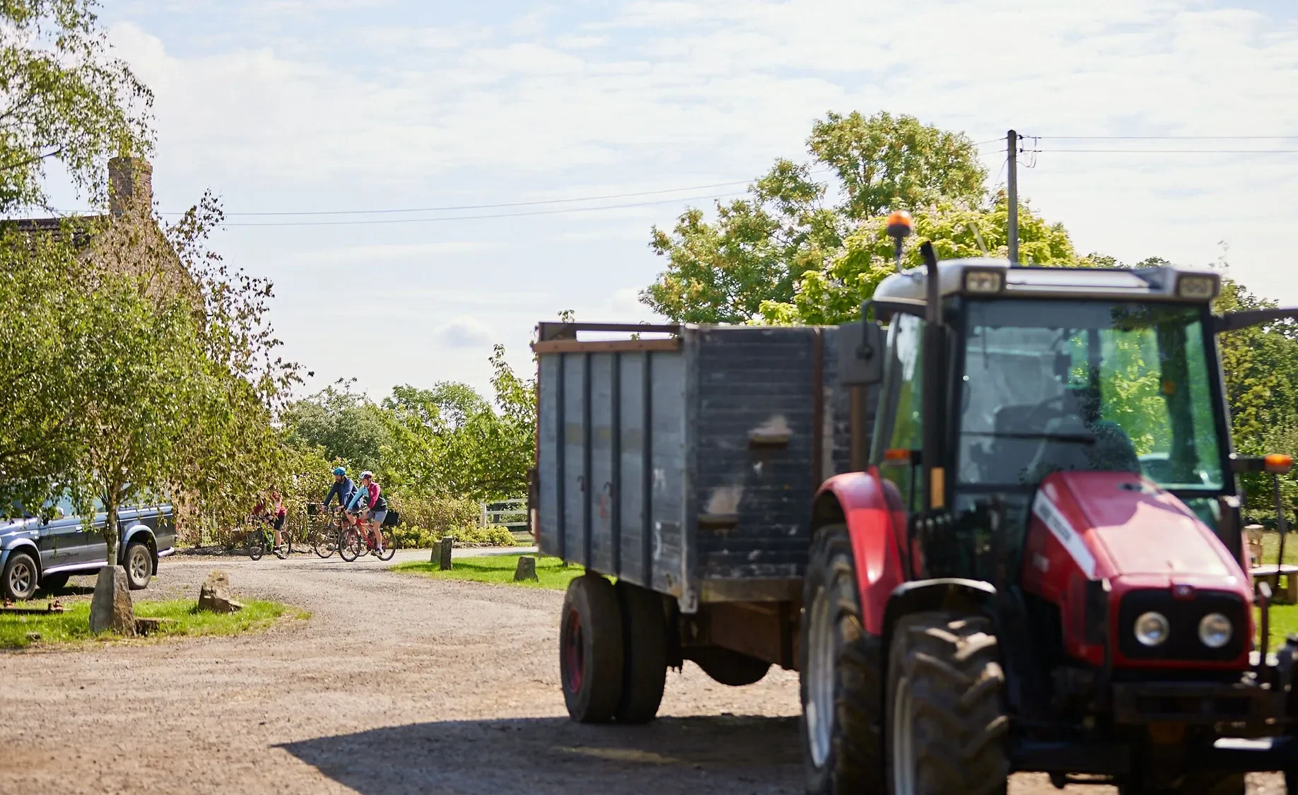 Red tractor with a blue trailer driving along a farm track