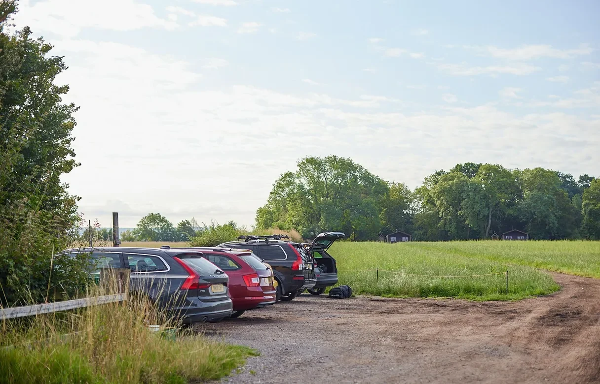 Cars parked in the car park beside an open field and farm track