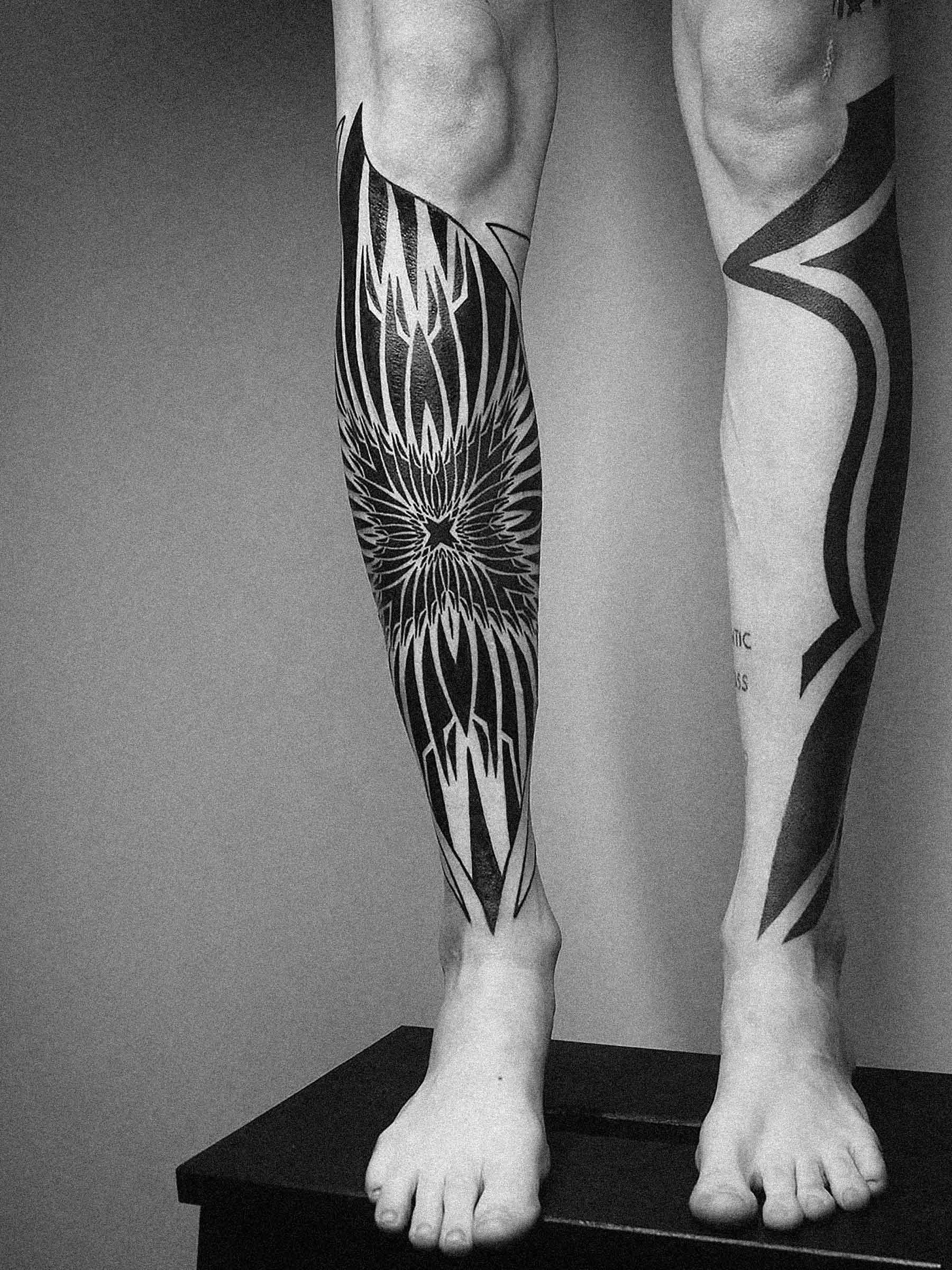 Tatuaż na piszczelach damskich, mocne czarne formy w stylu neotribal, blackwork. Praca wykonana przez Pawła Kurylaka | Zdjęcie wykonano w studio tatuażu w Gdańsku