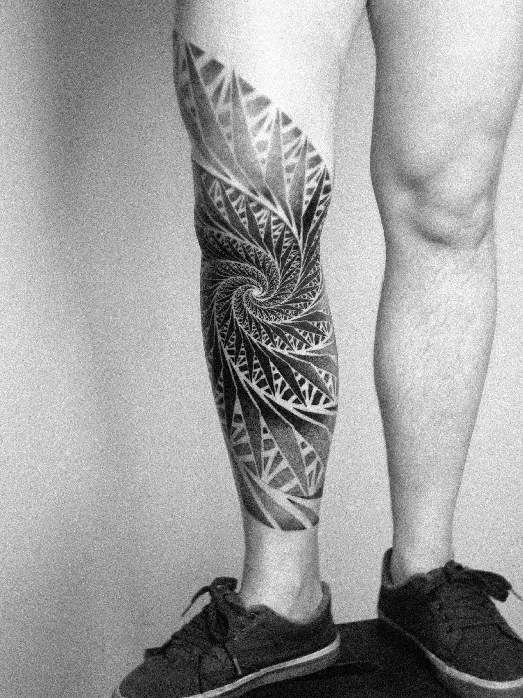 Tattoo on a man’s leg featuring a spiral fractal pattern. Paweł Kurylak — dotwork | Photo taken at a tattoo studio in Gdańsk