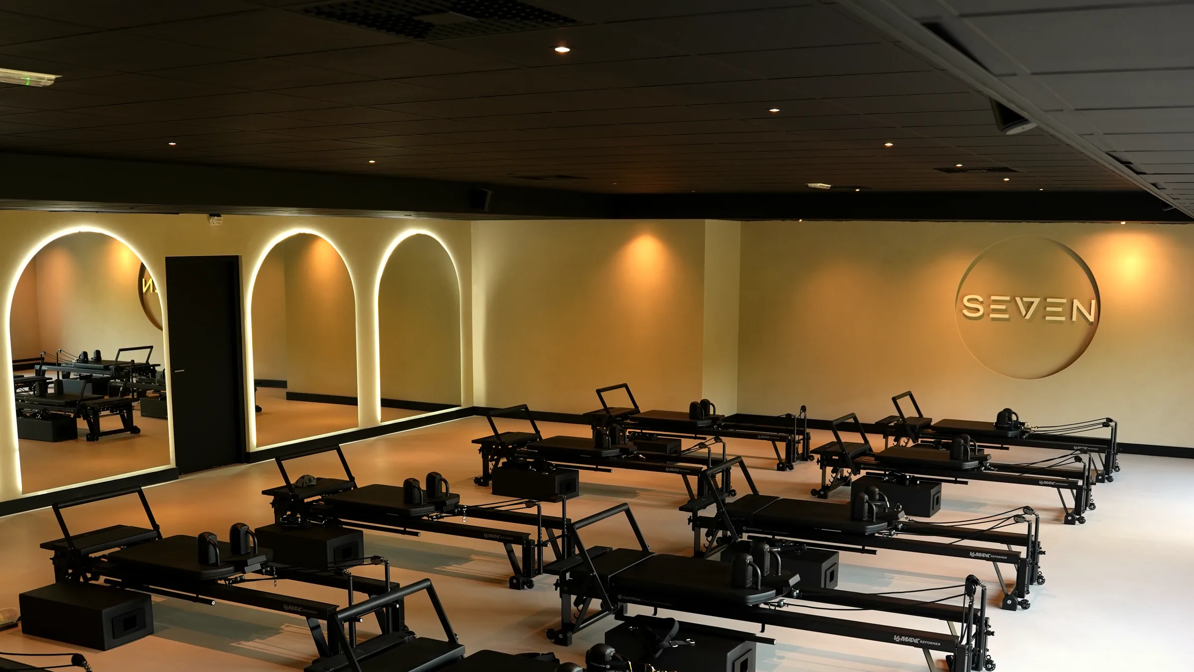 De studio van SEVEN Pilates in Almelo, met twaalf reformers en verlichte boogspiegels