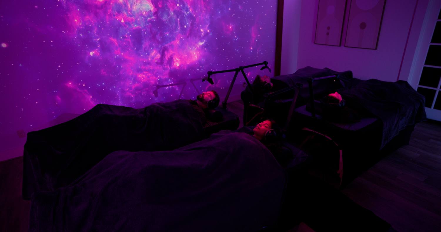 Two guests resting during a session, lit from above.