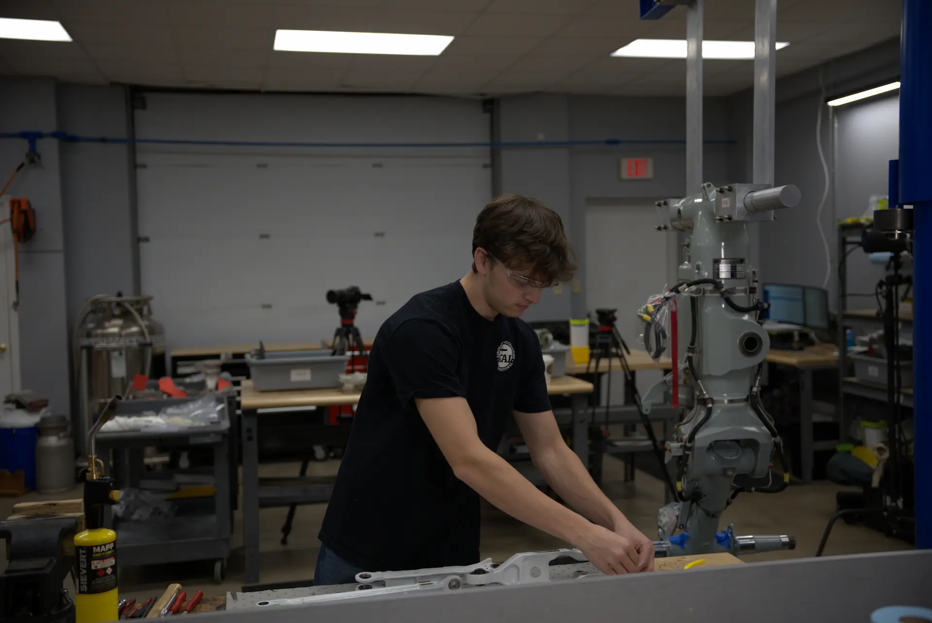 AAI technician working at a bench in the shop beside a landing gear assembly