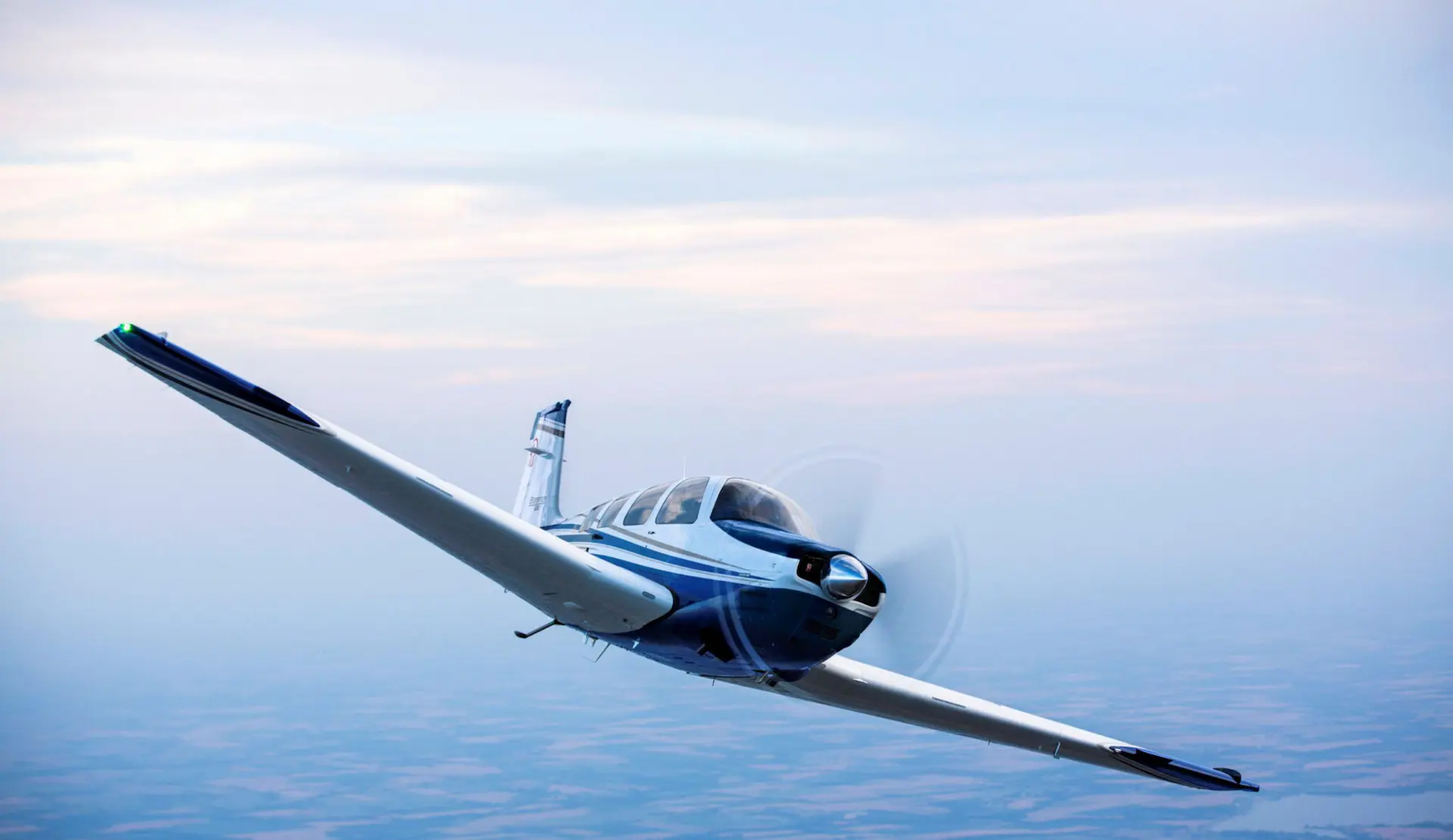 Beechcraft Bonanza banking in flight above a hazy landscape