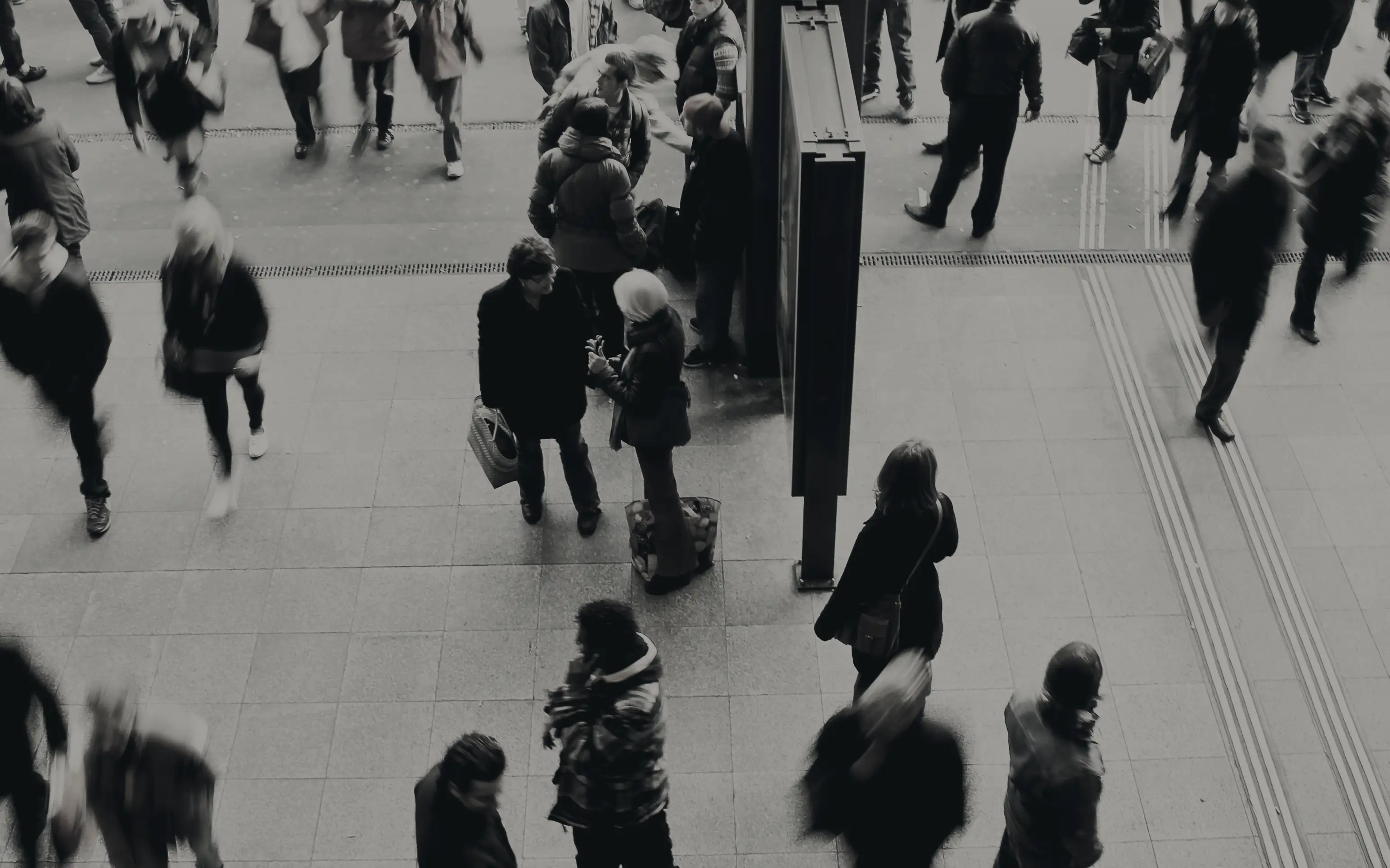 A crowd crossing a station concourse, seen from above