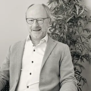 Anders Vik, principal for public infrastructure, seated beside a tall plant