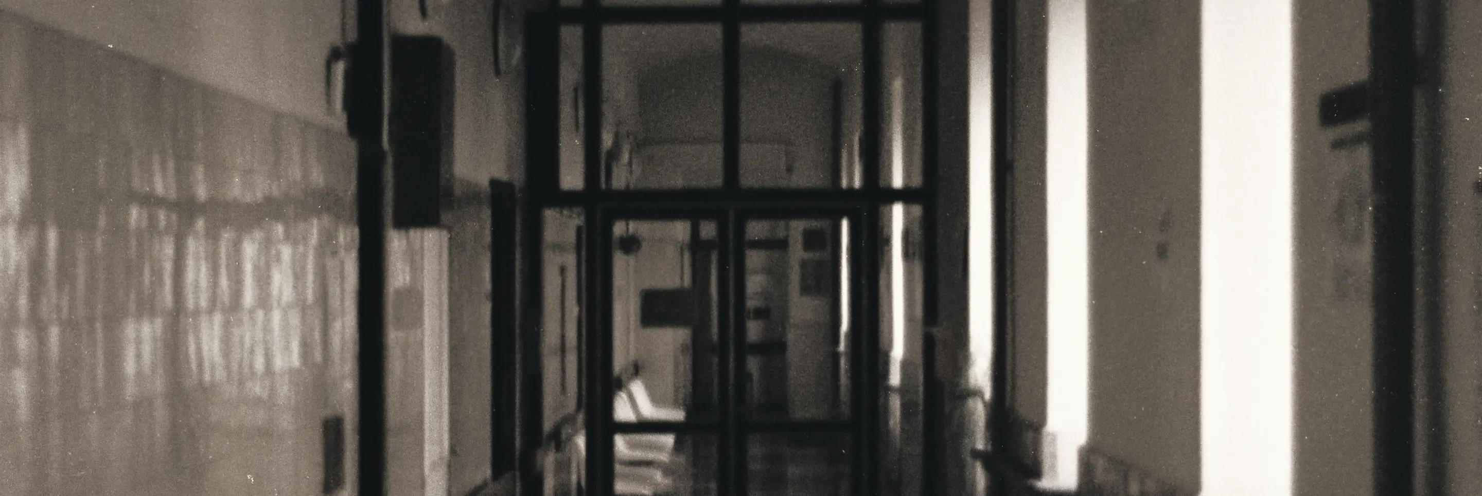 A hospital corridor with empty waiting chairs and glazed doors at the end