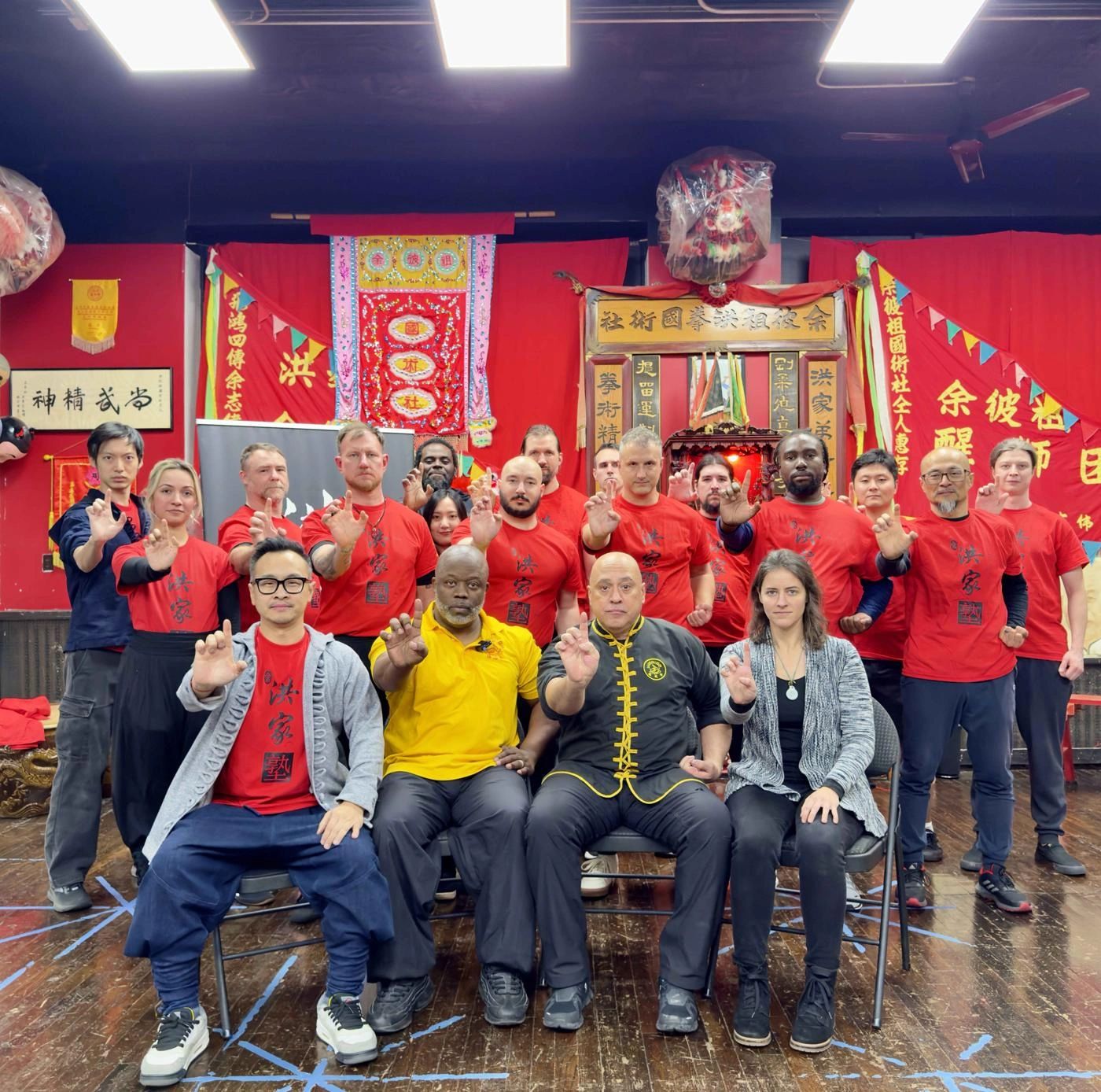Group photo of Yee's Hung Ga instructors and students in red school shirts at the association headquarters