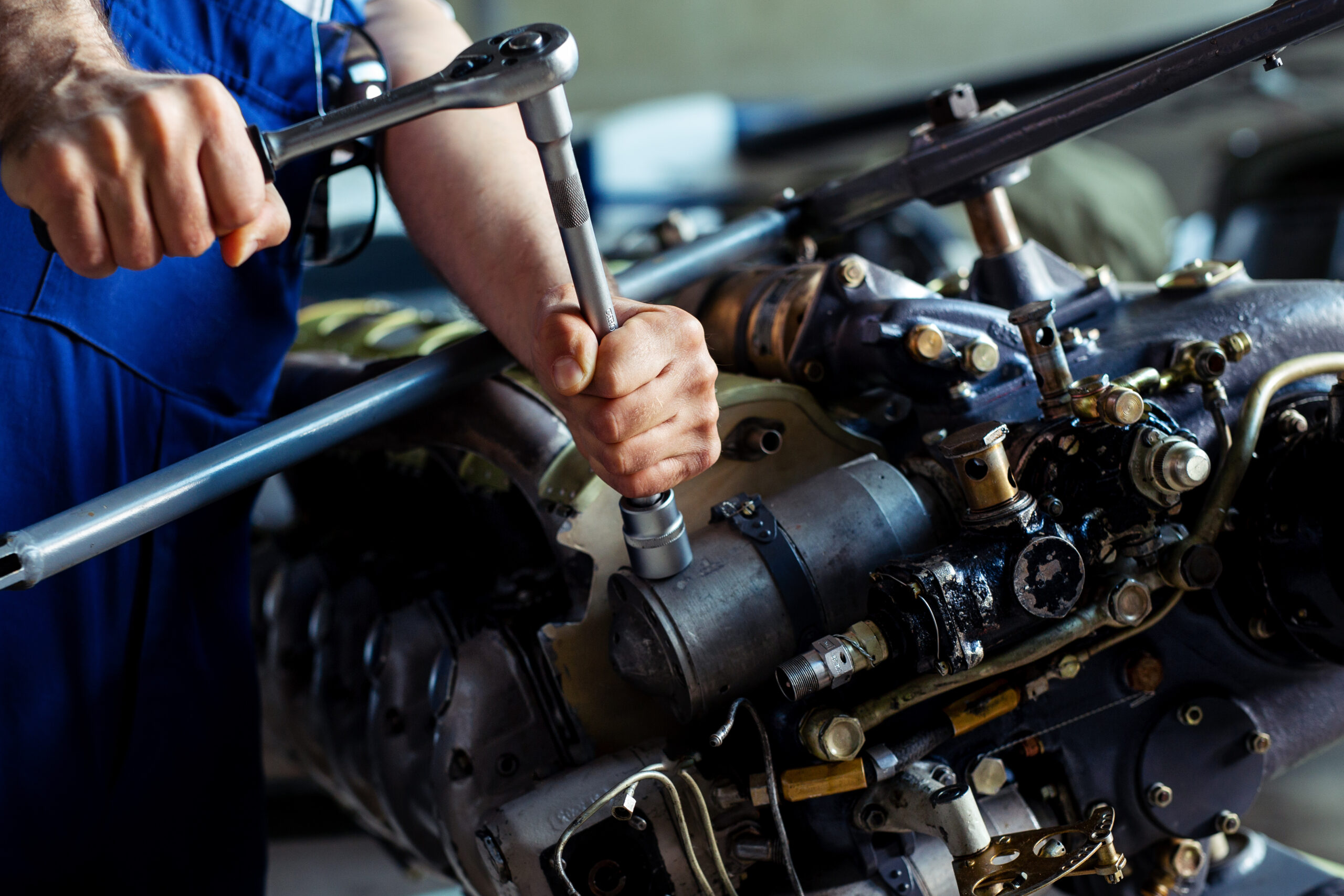 Aircraft mechanic using a torque wrench during engine maintenance.