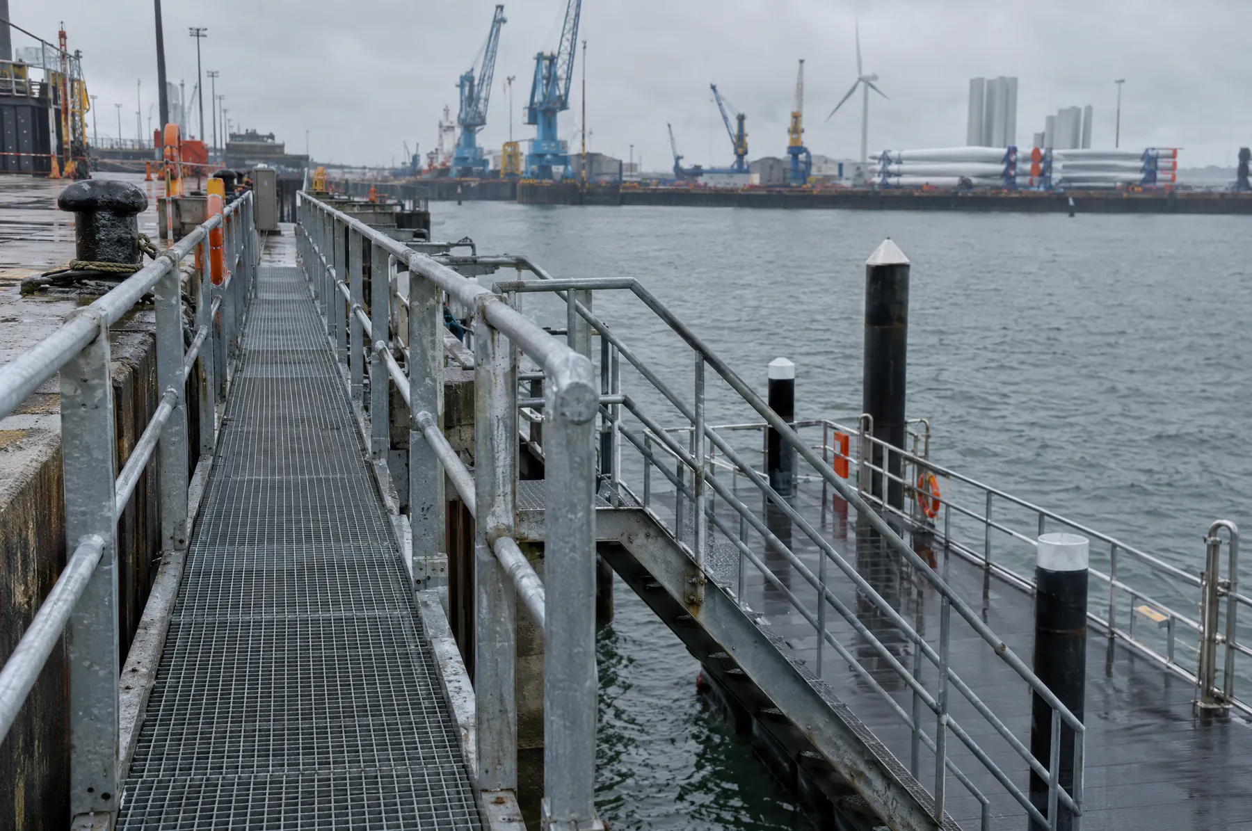 Illustrative image of a galvanised steel walkway and handrails on a quayside.