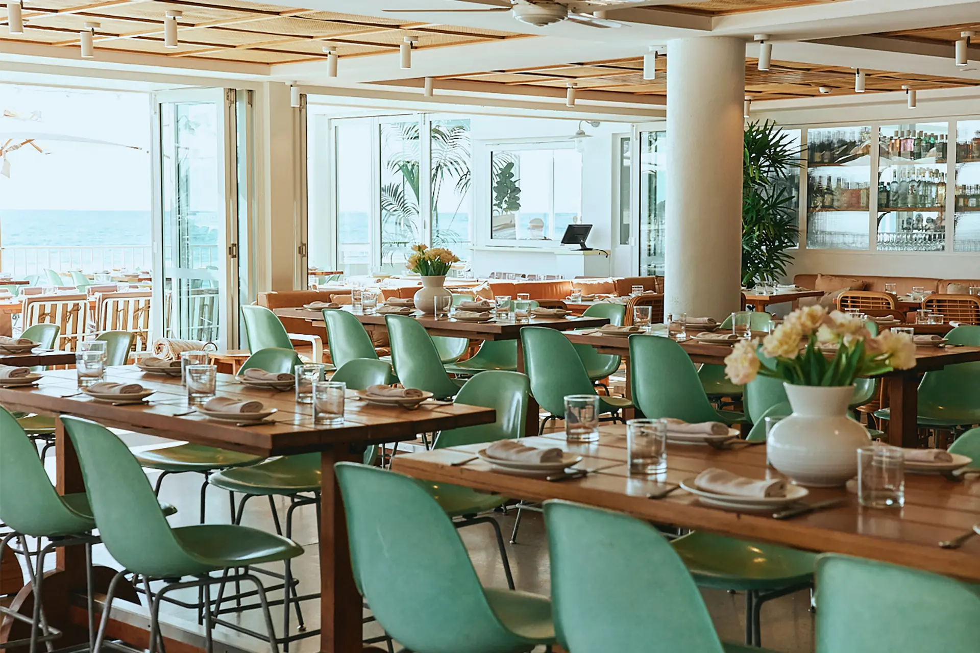 The Tropic dining room with green chairs, timber tables and fresh flowers