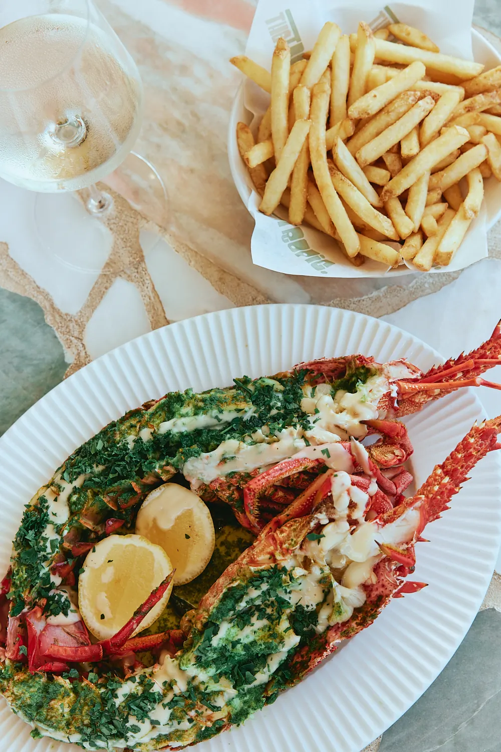 Grilled lobster with herb butter and lemon, served with fries and white wine at The Tropic