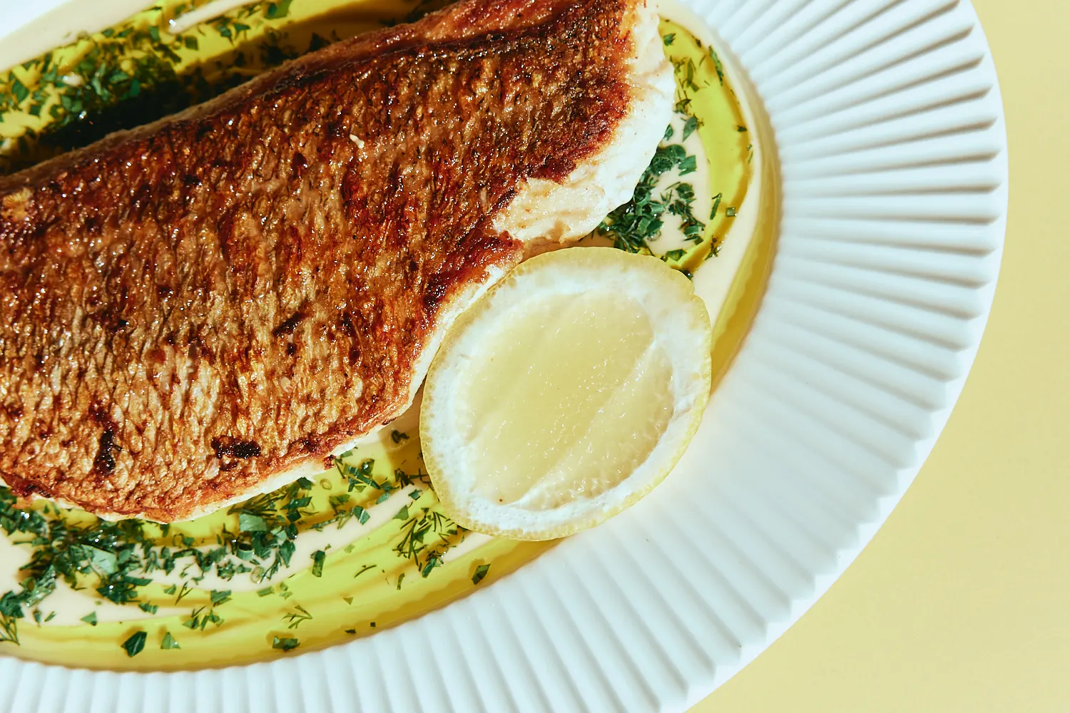 Crisp-skinned fish fillet with herb oil and lemon at The Tropic