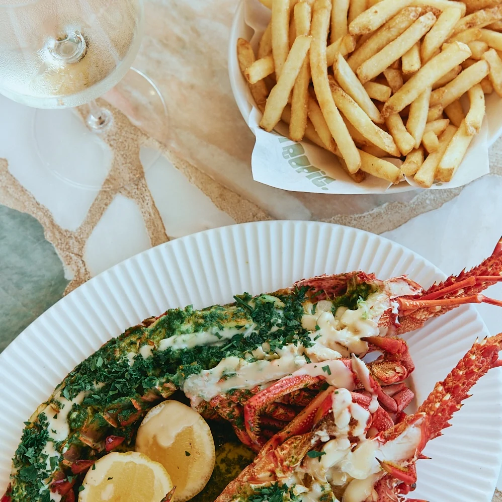 Grilled lobster with herb butter and lemon, served with fries and white wine at The Tropic