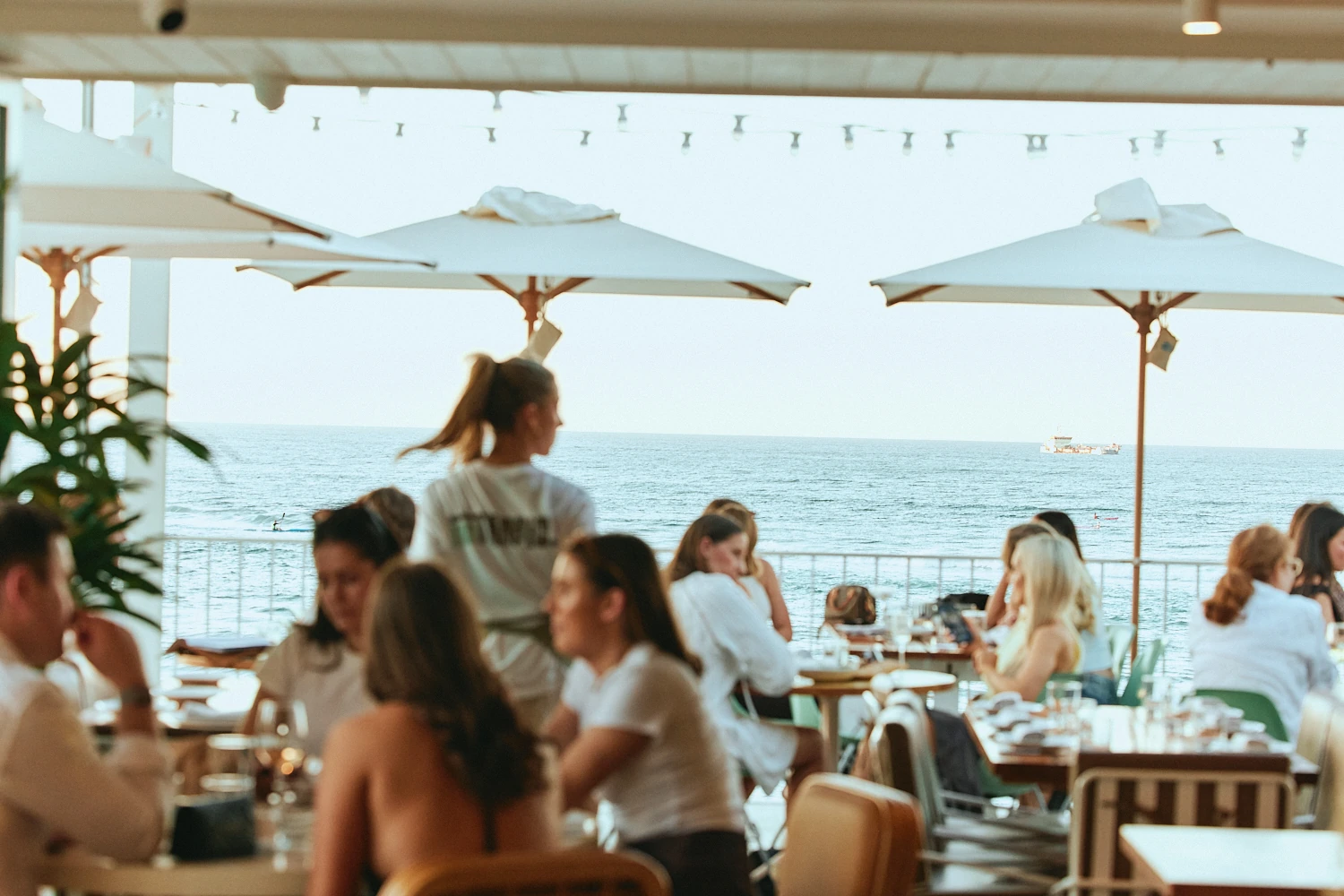 Guests dining on The Tropic terrace with the ocean behind