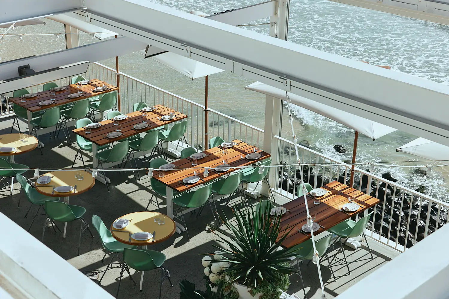 Aerial view of The Tropic terrace tables above the rocks and surf