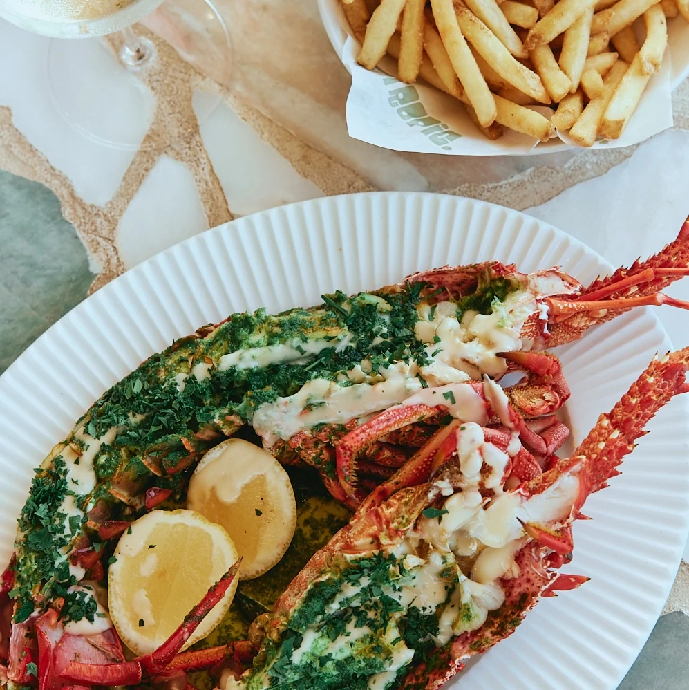 Grilled lobster with herb butter and lemon, served with fries and white wine at The Tropic