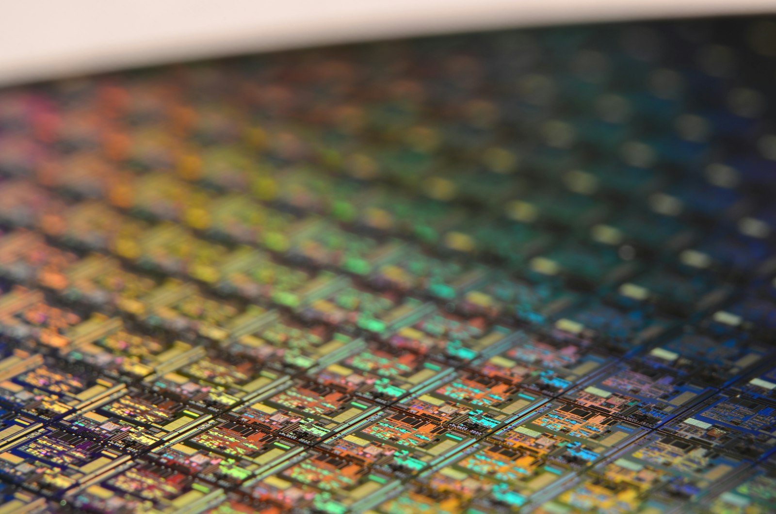 Edge of a silicon wafer showing rows of iridescent dies