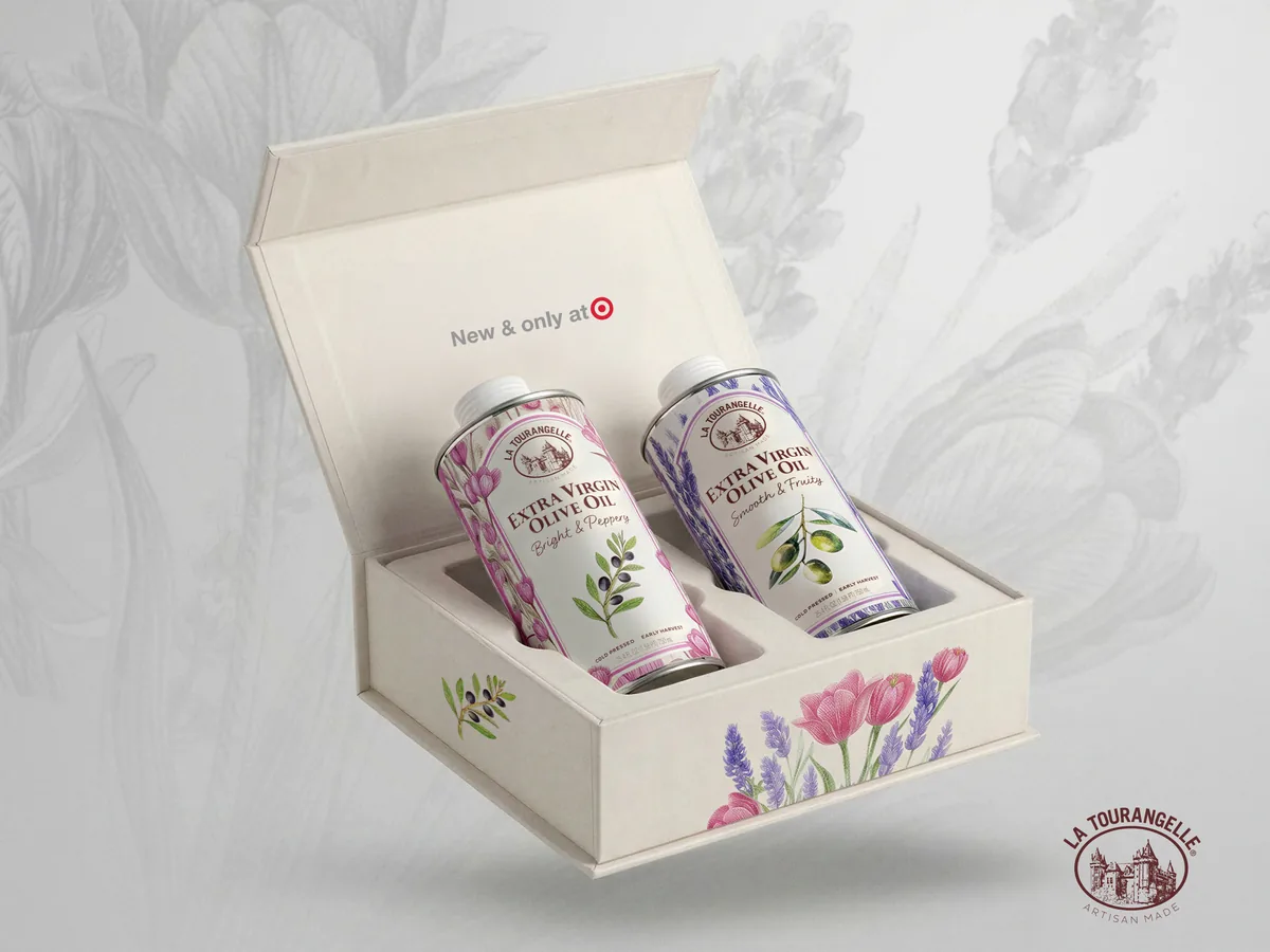 Open gift box for La Tourangelle Floral Collection extra virgin olive oil, cream magnetic-close box with tulip illustrations revealing Bright and Peppery and Smooth and Fruity tins inside, New and Only at Target callout on lid interior