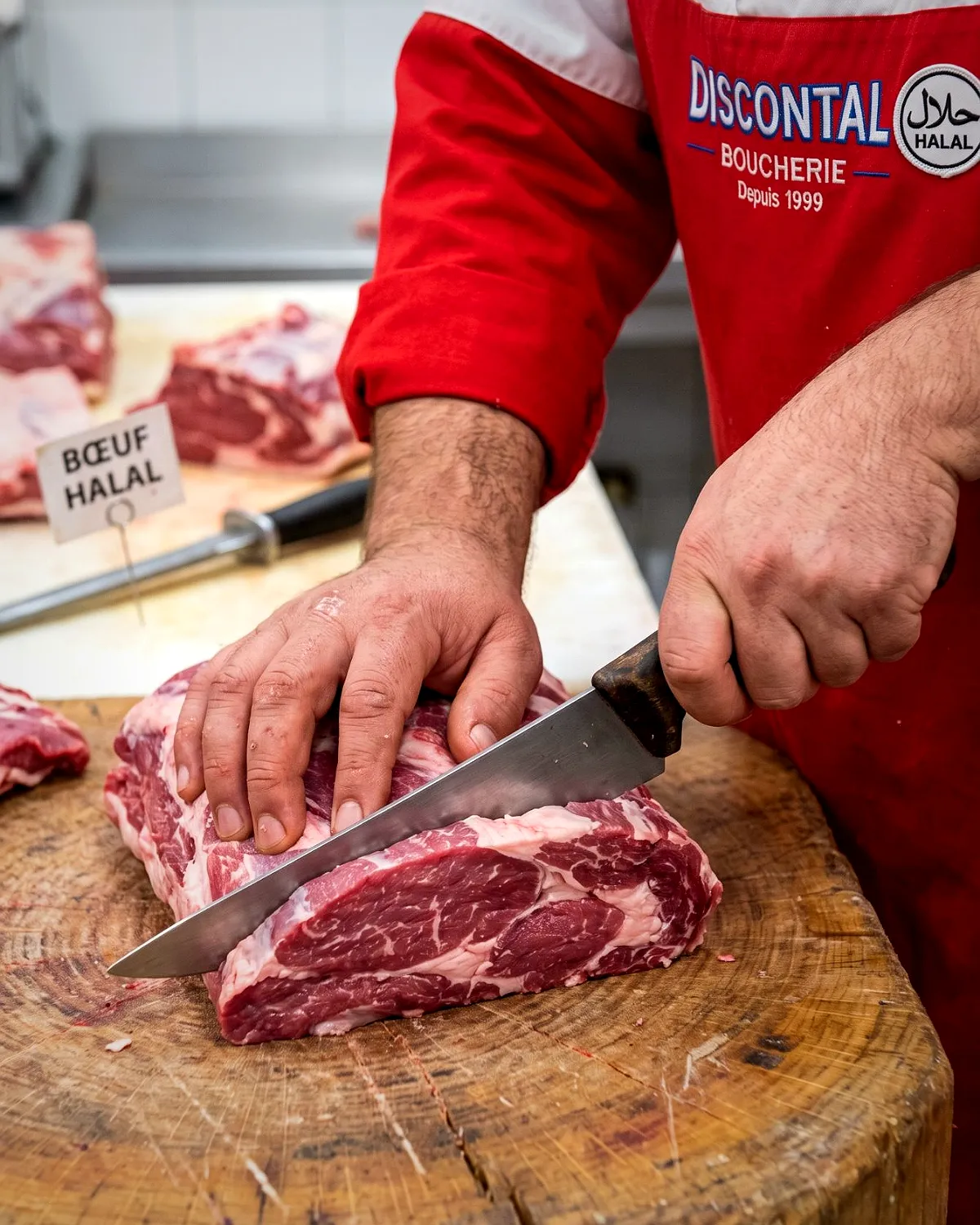 Le boucher découpe une pièce de bœuf halal sur le billot