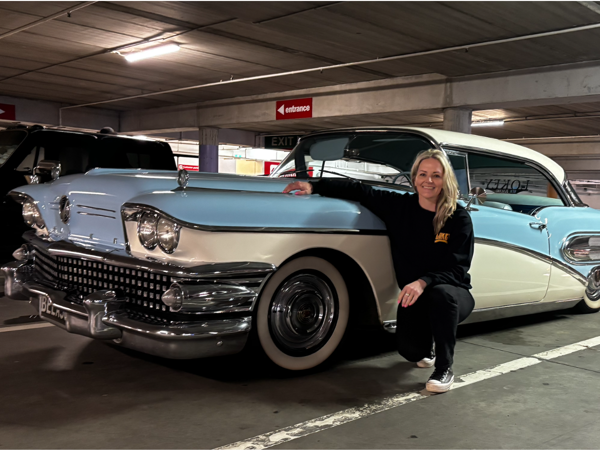 Kendyl Coleman, marketing consultant, crouched beside her blue and white 1958 Buick