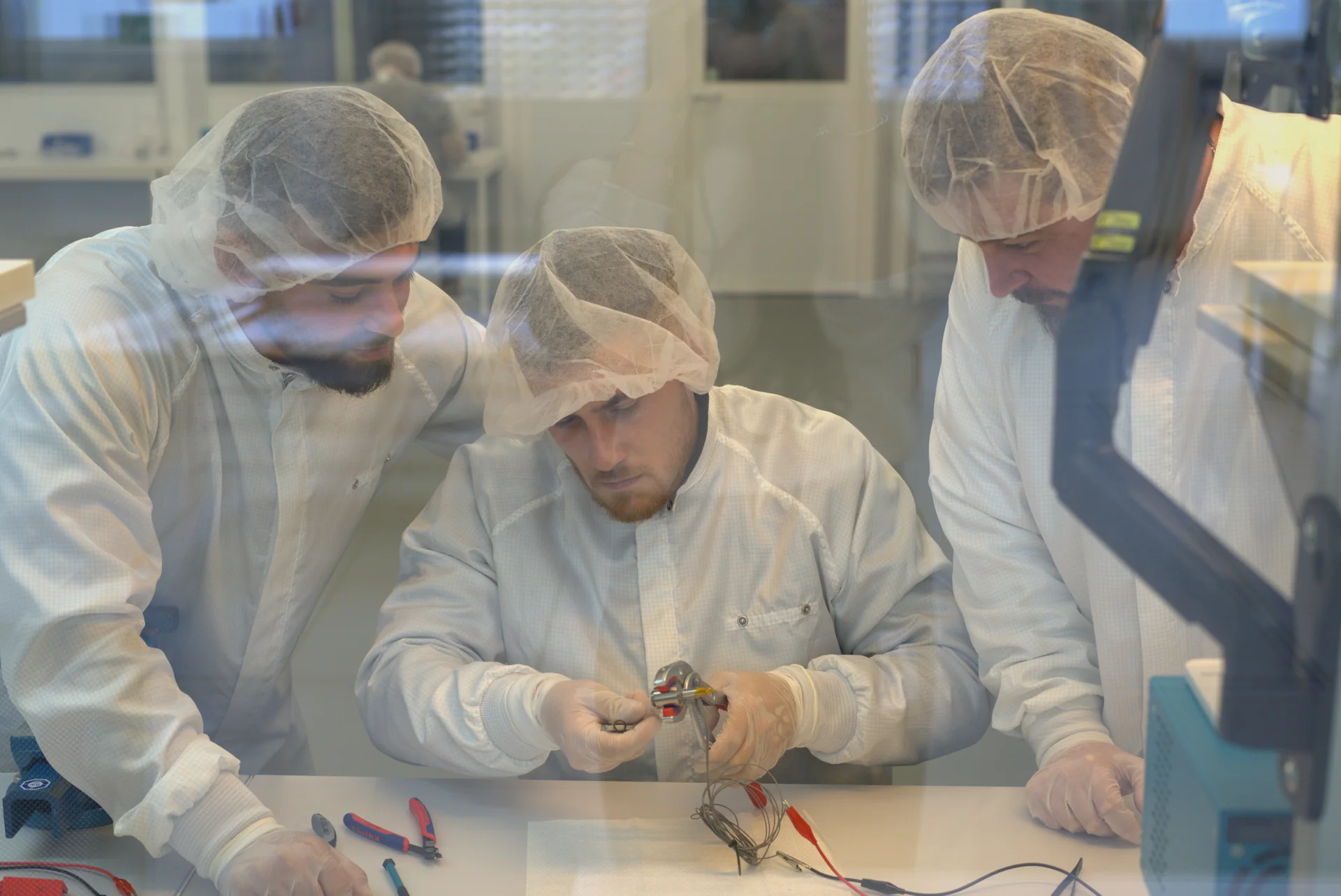 Technicians assembling a component in a cleanroom