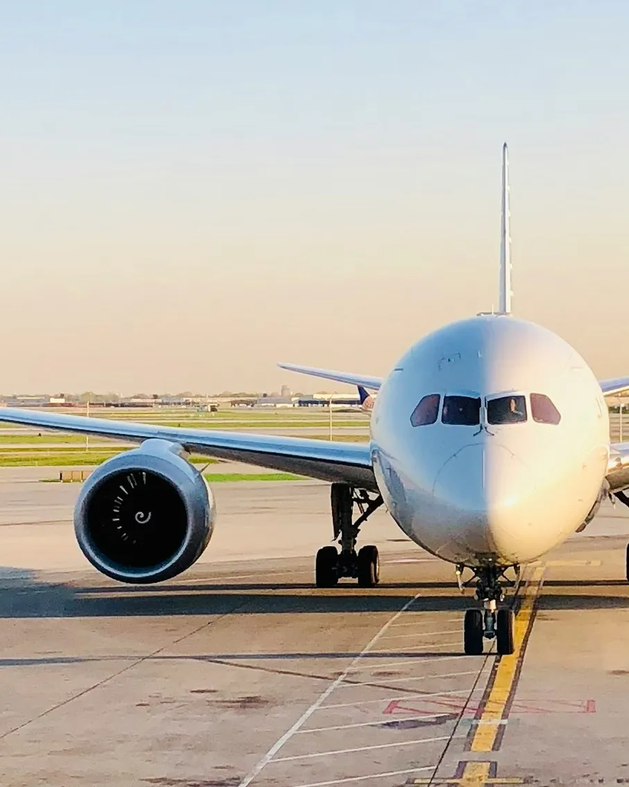 Front view of a white commercial airplane parked on airport tarmac at sunset.
