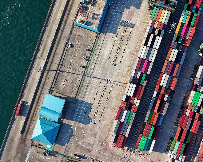 Aerial view of a port with colorful shipping containers and nearby water.