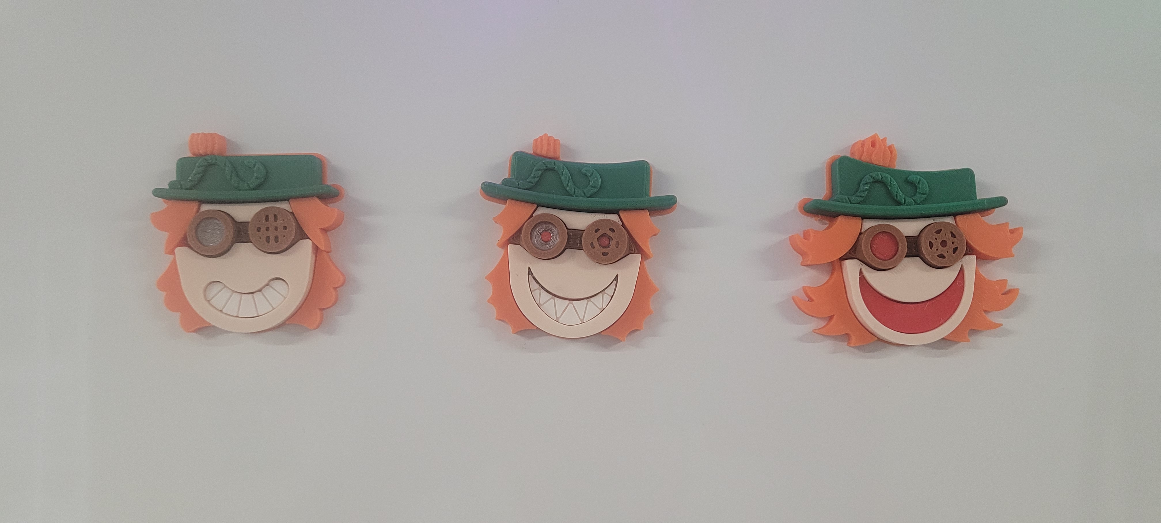 Three 3D-printed pumpkin character magnets with goggles and green hats