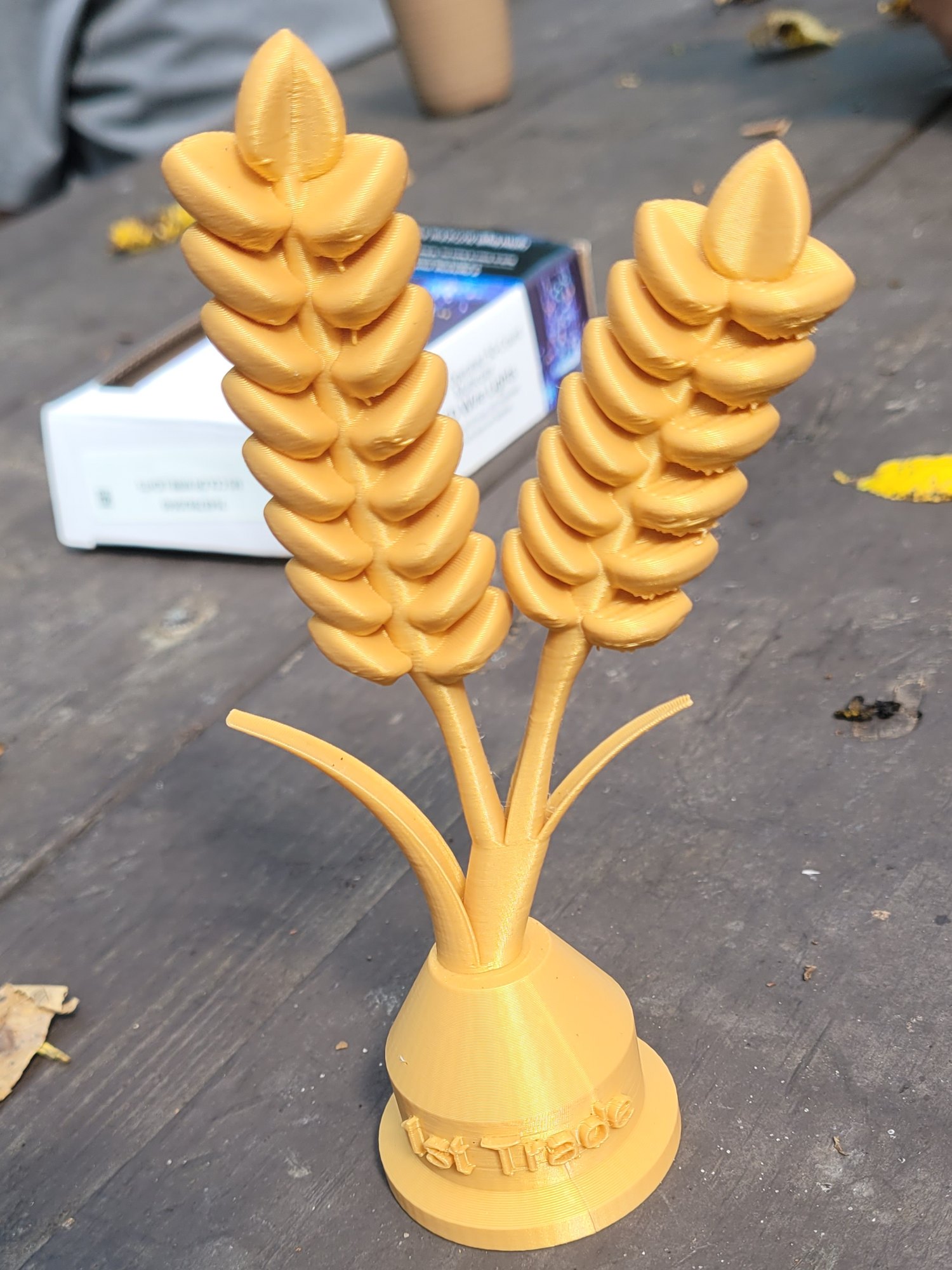 Gold 3D-printed wheat trophy with 1st Trade printed on its base
