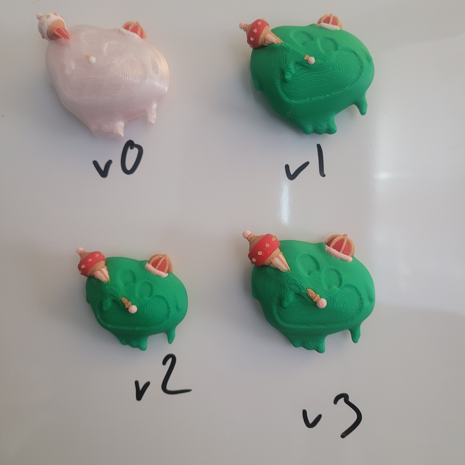 Four 3D-printed versions of a character design, labeled v0 to v3, showing how the design was refined