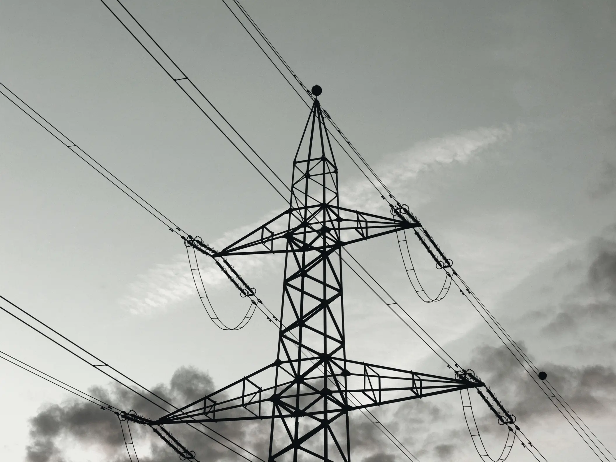 A switchyard at a substation, gantries and insulators against a flat sky