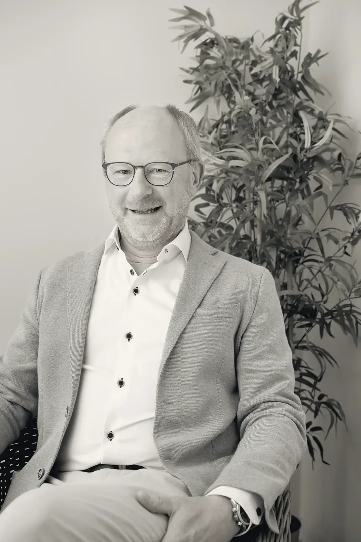 Anders Vik, principal for public infrastructure, seated beside a tall plant