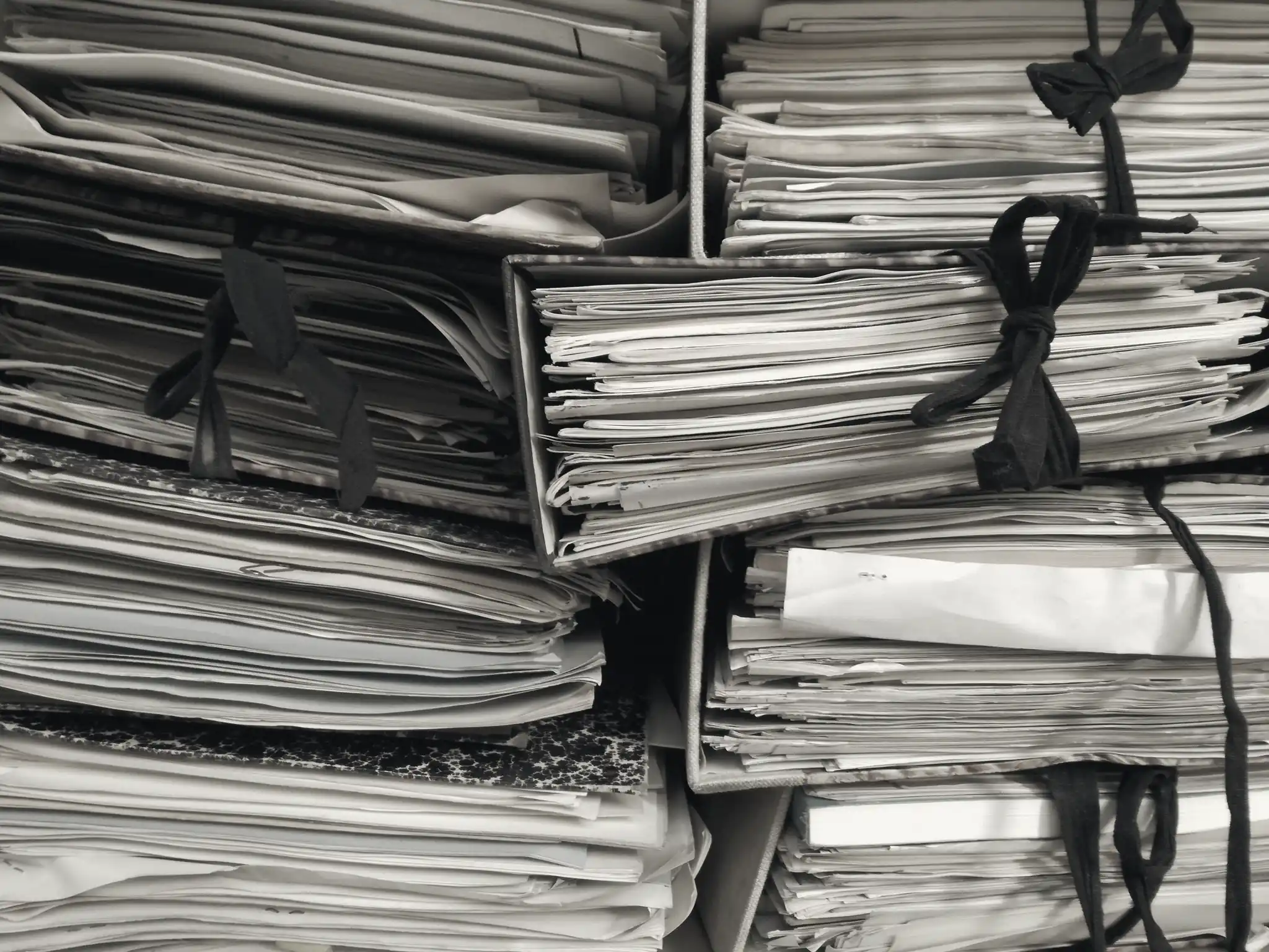 Bundles of papers tied shut with cloth ties, stacked on shelves