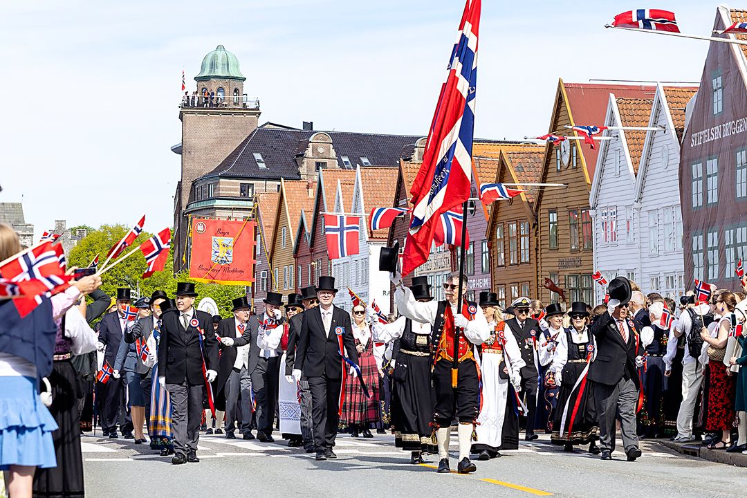 Flaggbærere og deltakere i 17. mai-prosesjonen foran Bryggen i Bergen.