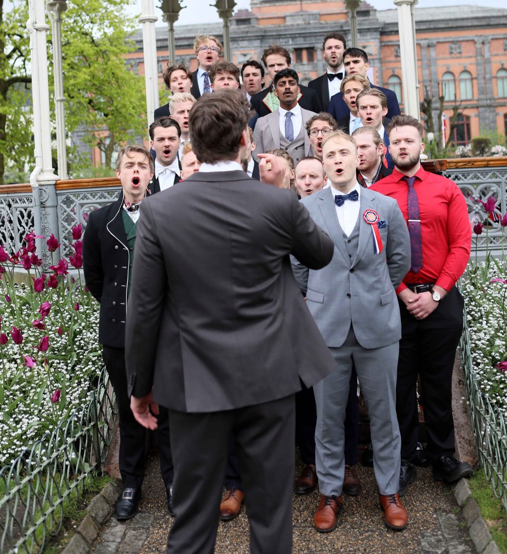 Mannskor med dirigent ved musikkpaviljongen – 700272454_10243387330195892_8474426238483263380_n