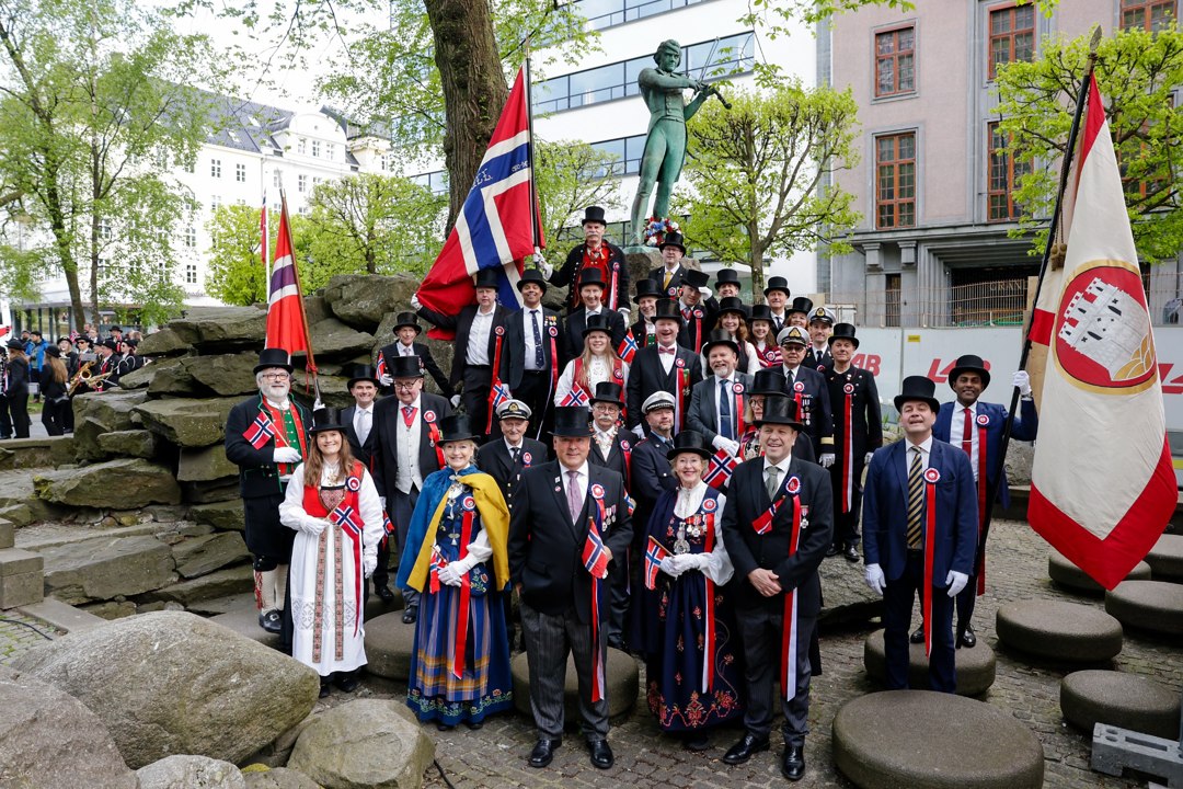 Deltakere samlet ved en statue med norske flagg – _SKR5132