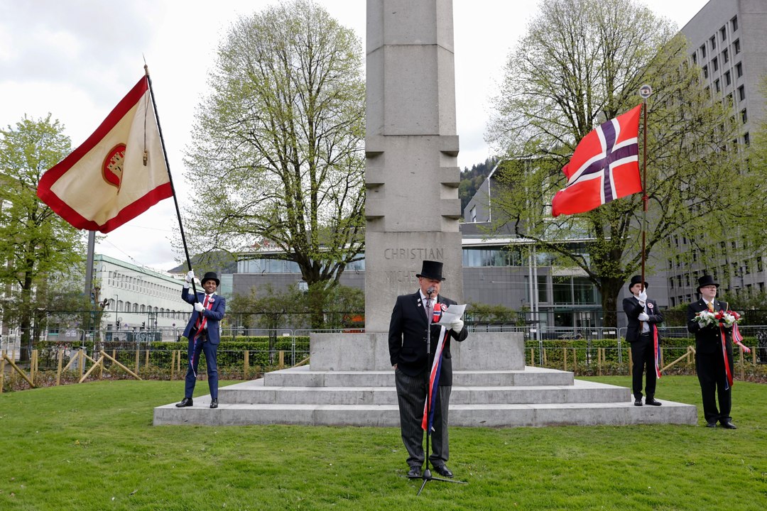 Trompetist og flaggbærere foran en bauta – _SKR5220