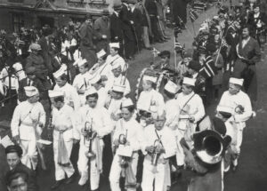 Et av byens guttemusikkorps i flagg-toget ned Skansesvingene, ca. 1930. 17. mai-komiteens arkiv. Manuskript- og librarsamlingen. Spesialsamlingene. Universitetsbiblioteket i Bergen.