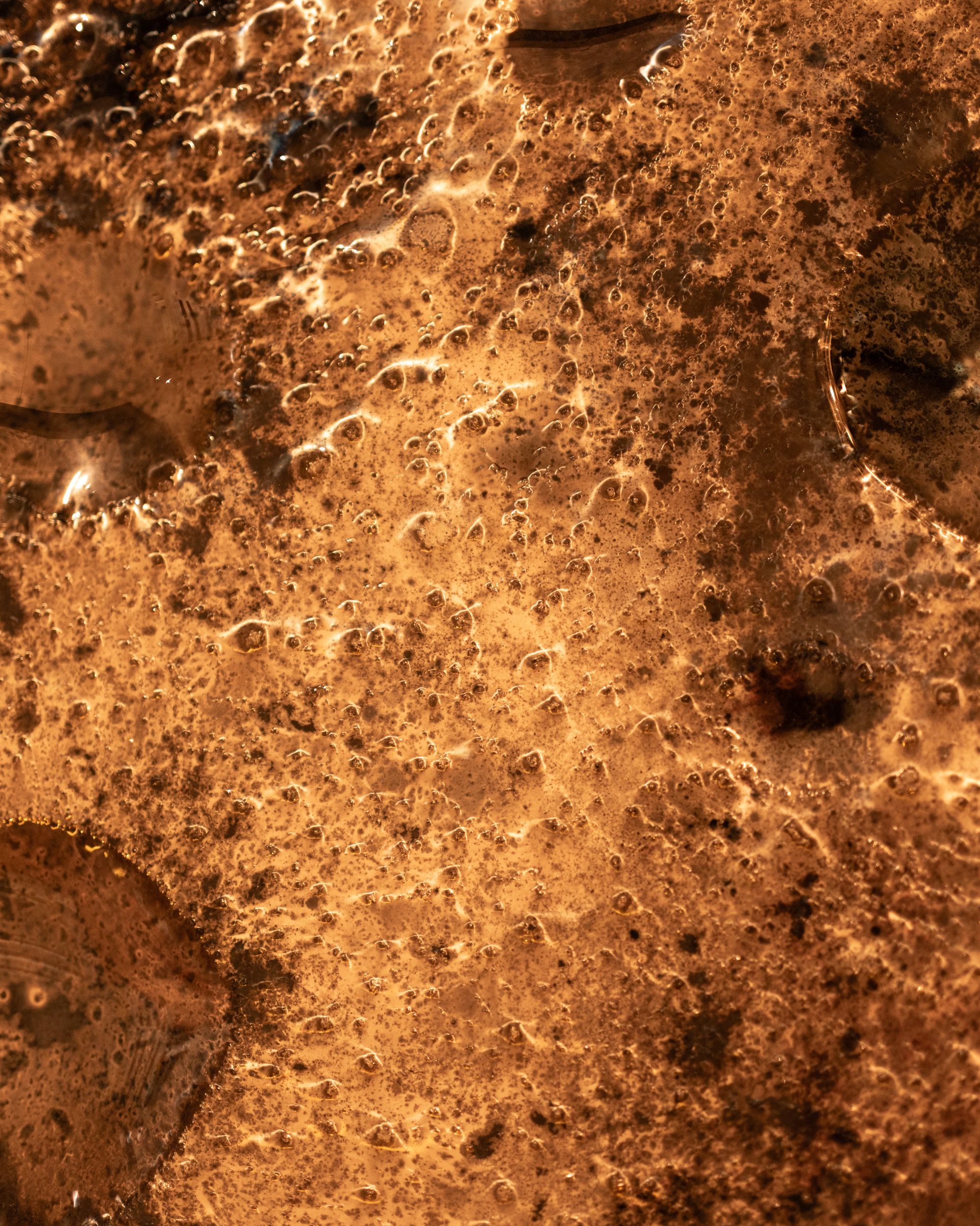 Pitted silvered glass surface in warm light, close up
