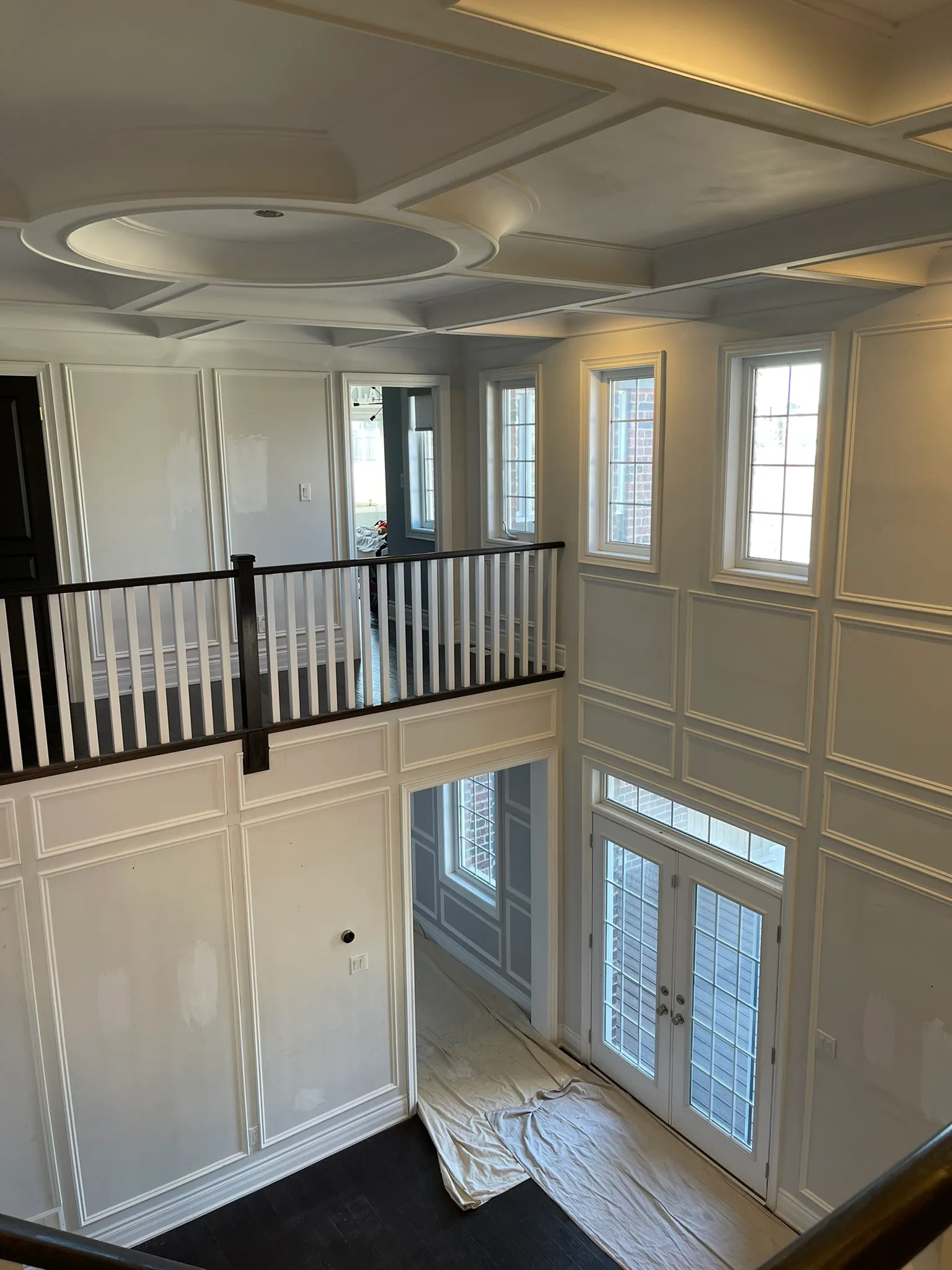 Custom wall panelling, window trim and coffered ceiling in a two-storey foyer