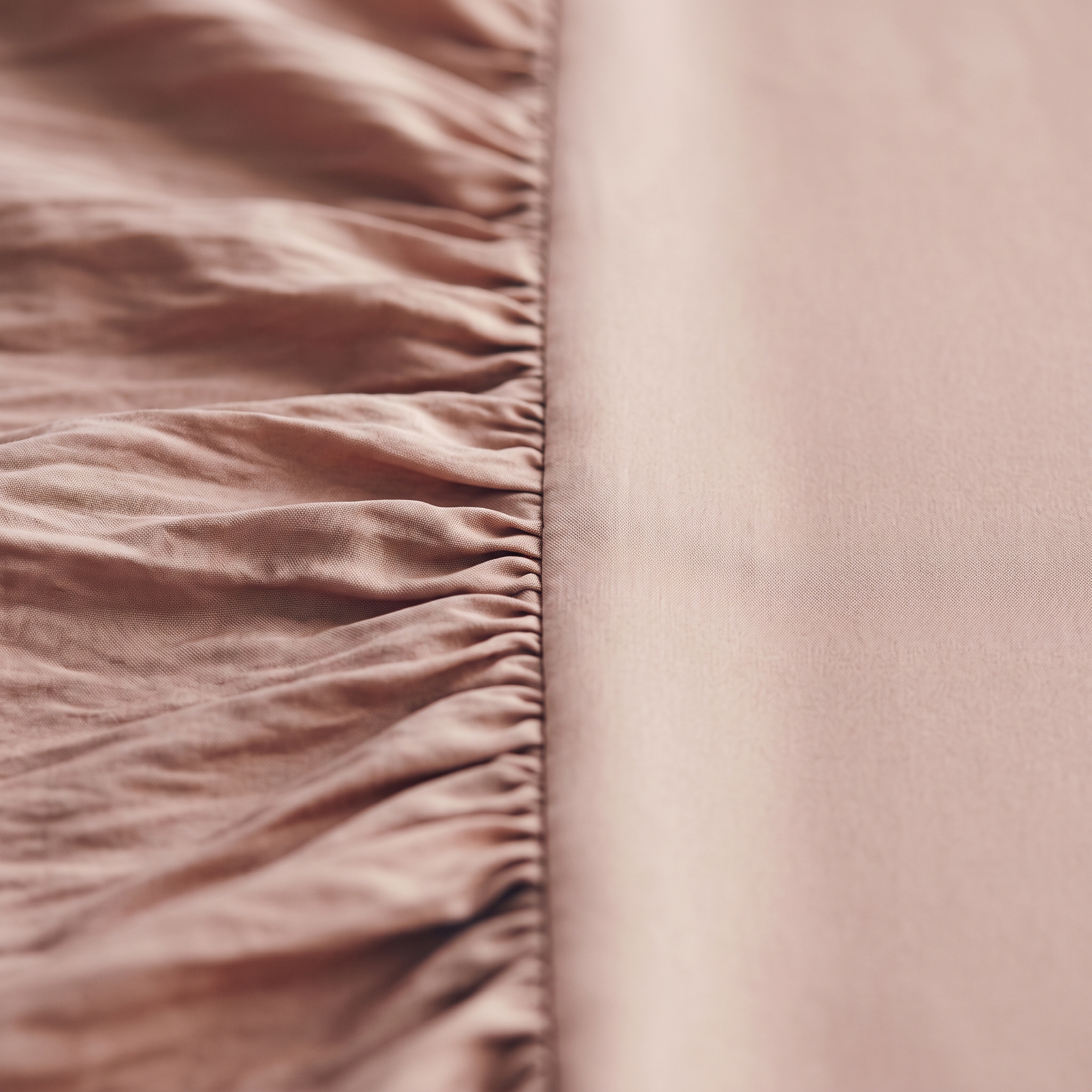 Blush-pink fabric, gathered into soft creases on one side and falling smooth on the other