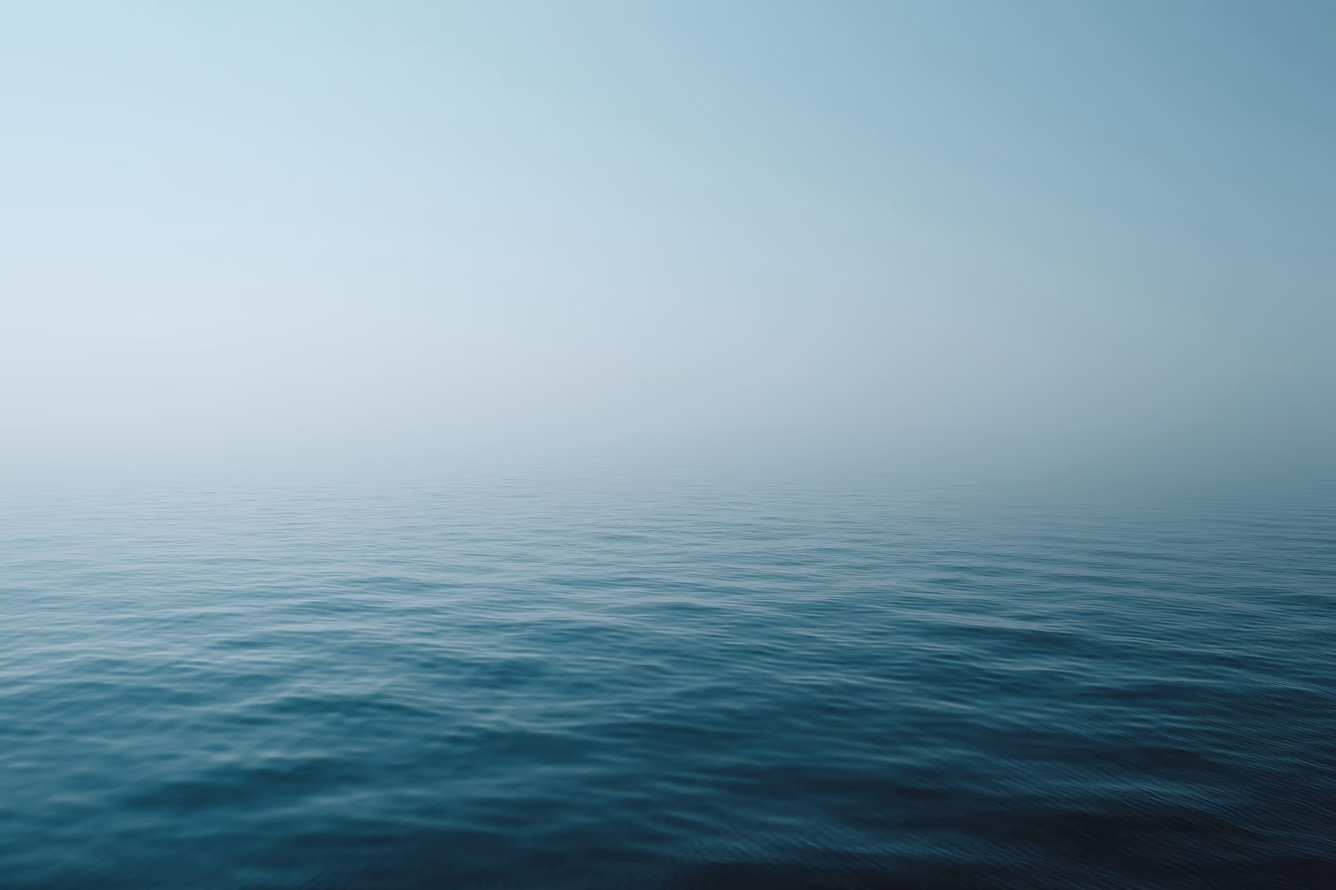 Calm ocean water under a hazy sky with a tranquil and serene atmosphere.