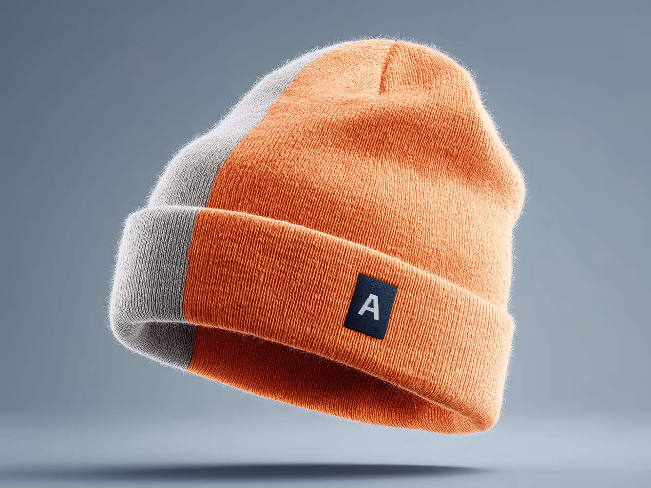 Orange and gray knitted beanie floating over a soft blue background.