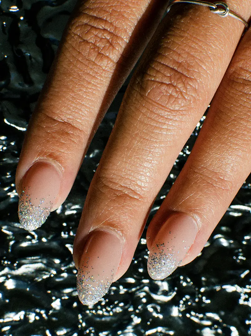 Photo of hands with sparkly painted manicure over a water background