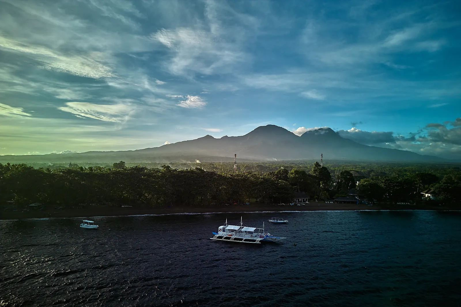 Dive boats off the Dauin coast with mountains in the background